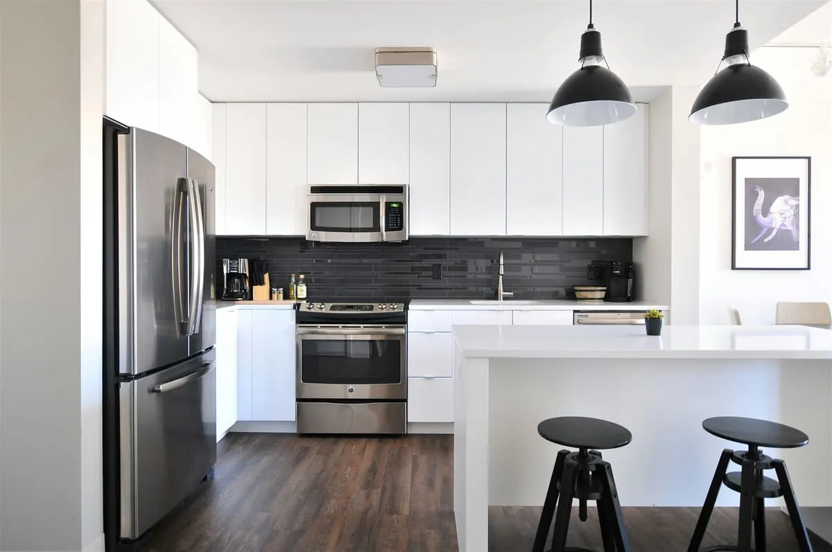 Bright white kitchen with stainless steel appliances and black bar stools